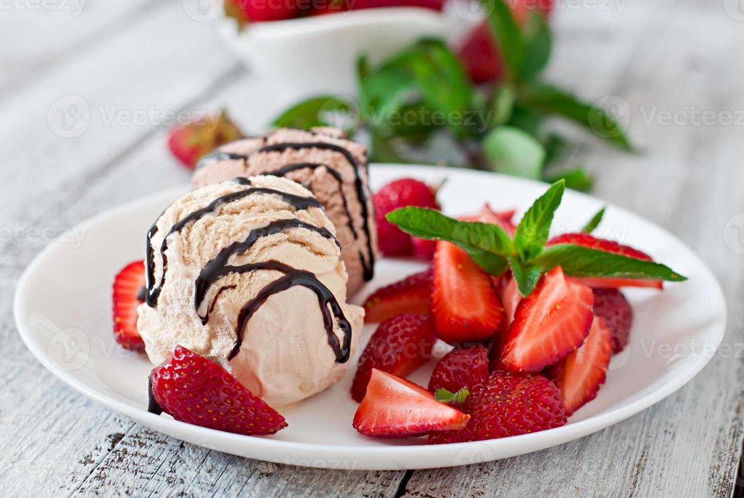 Eis mit Erdbeeren und Schokolade auf einem weißen Teller foto
