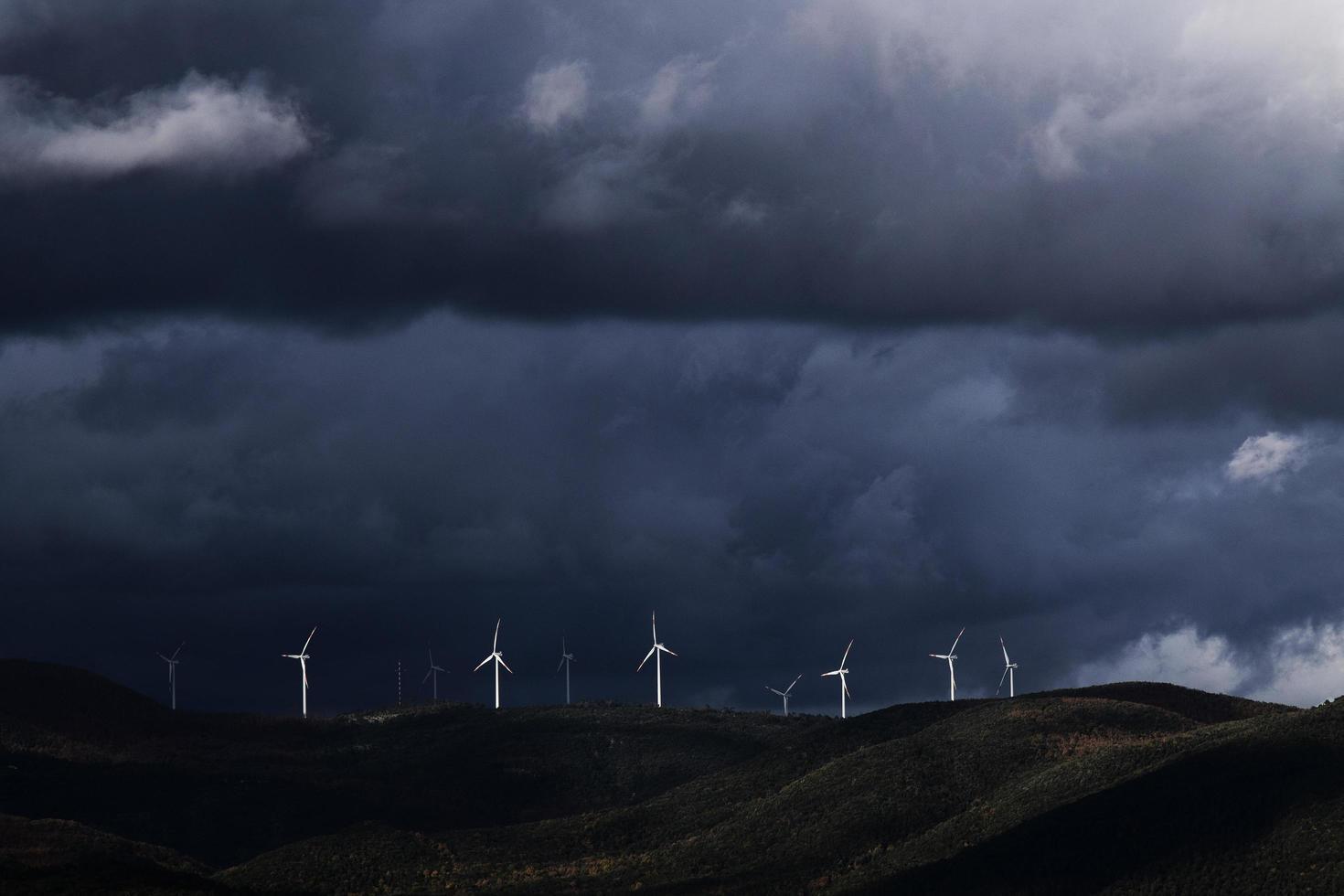 Windkraftanlagen auf Hügel unter schweren Wolken foto