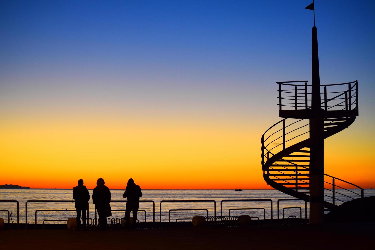 Silhouette von drei Personen, die einen Sonnenuntergang beobachten foto