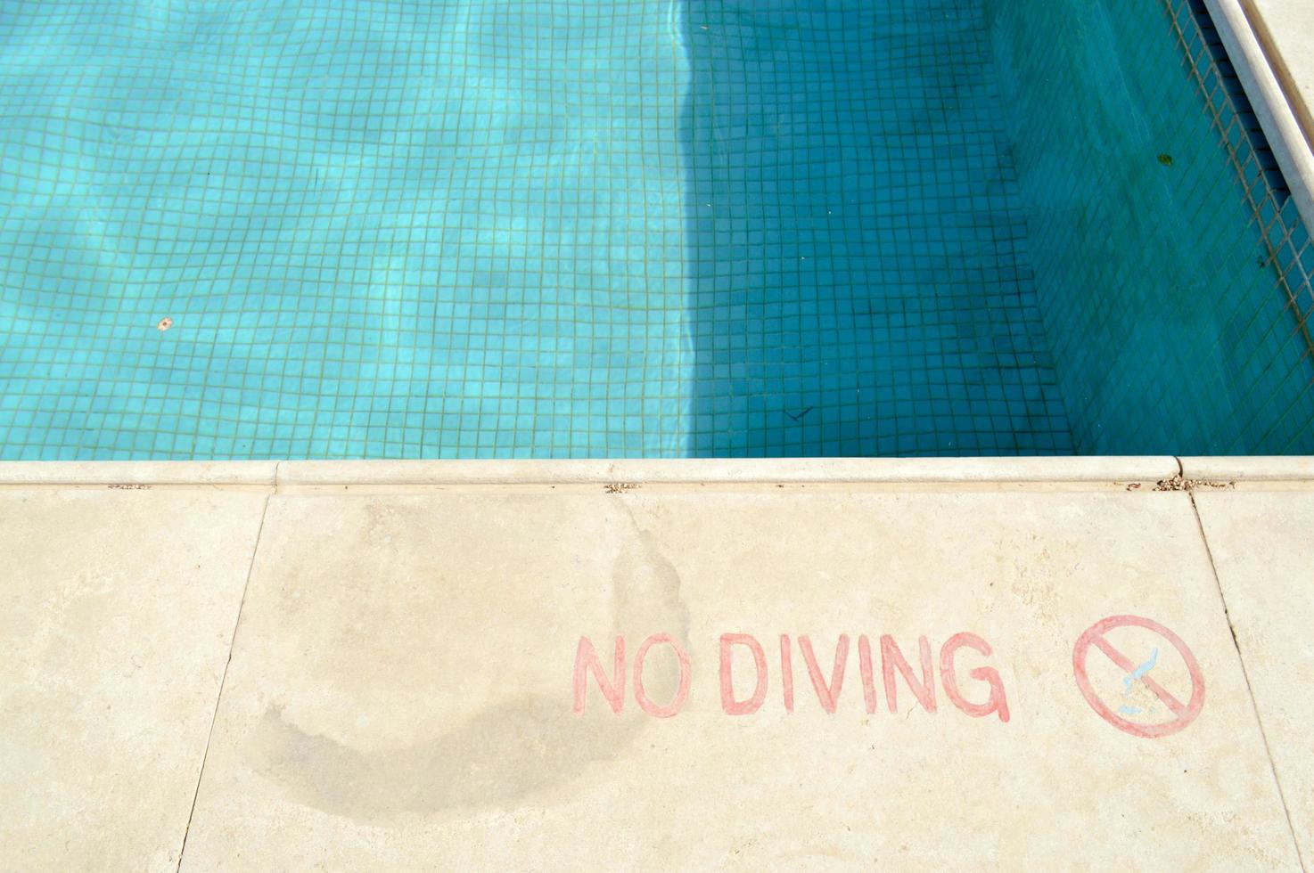 rote Farbaufschrift kein Tauchen aus Sicherheitsgründen auf dem Hintergrund des Pools in einem tropischen warmen Badeort und Kopierraum foto