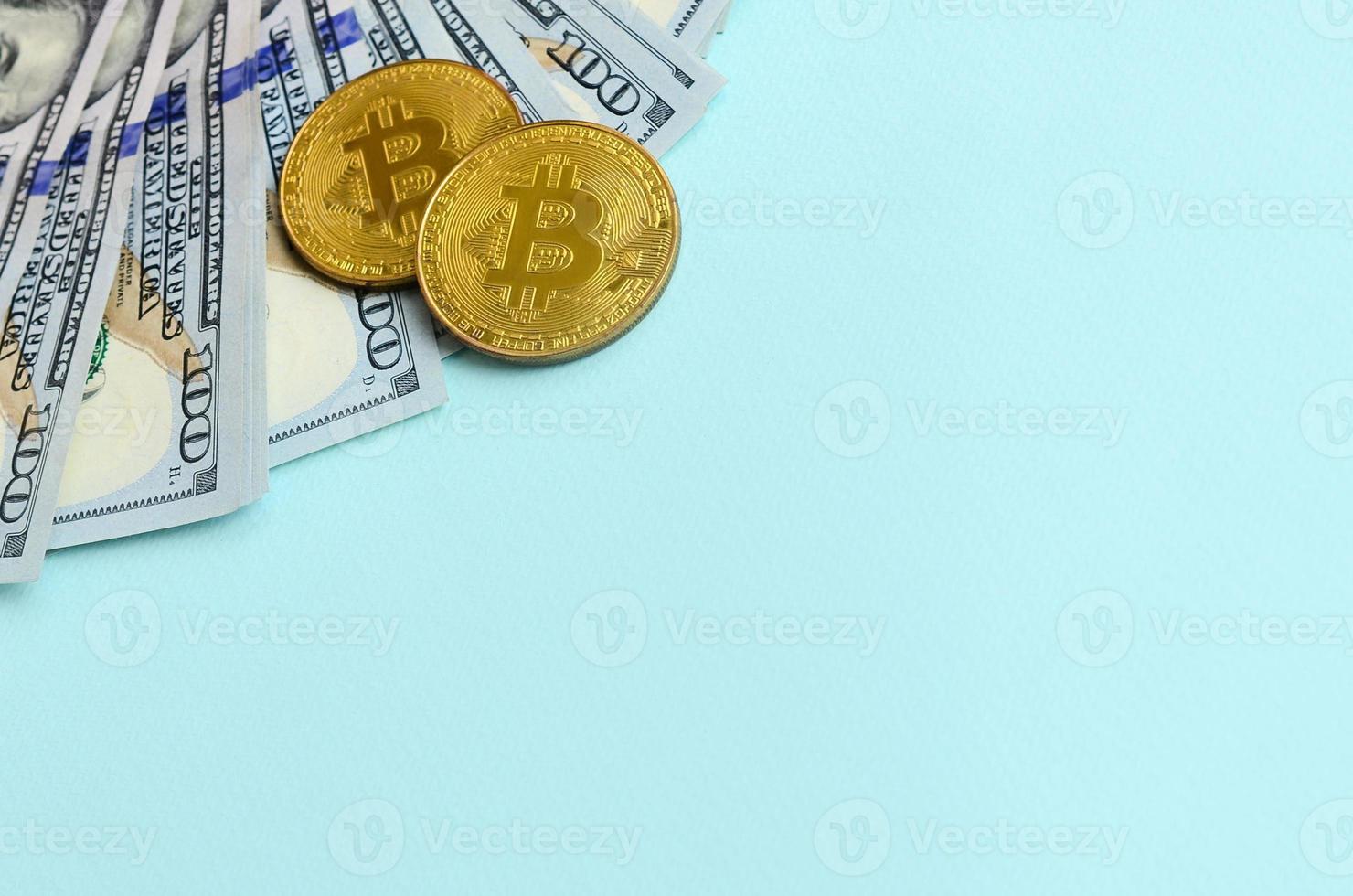 goldene bitcoins und hundertdollarscheine liegen auf hellblauem hintergrund foto