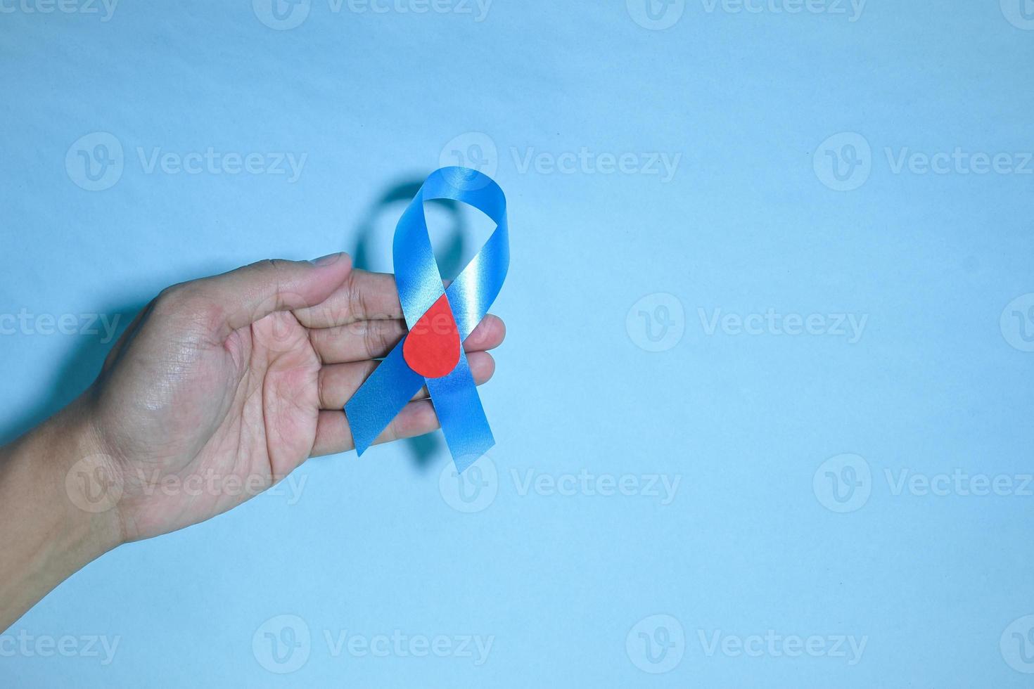 Draufsicht blaues Bandbewusstsein mit rotem Blutstropfen in den Händen des Mannes isoliert auf blauem Hintergrund. 14. November, Weltdiabetestag. Exemplar foto