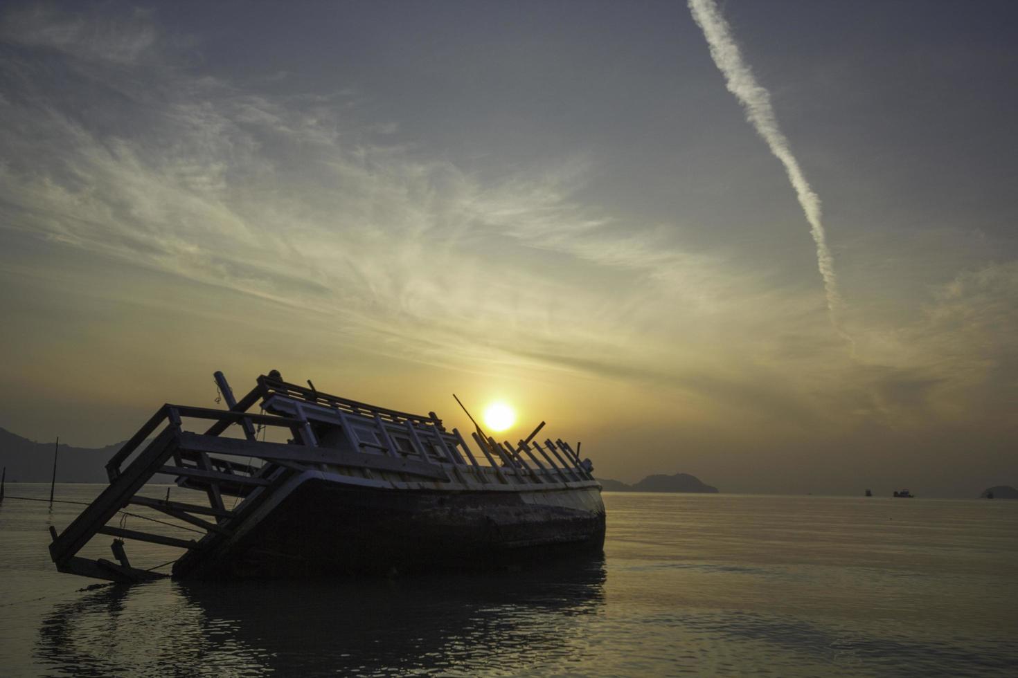 sinkendes Boot im Sonnenaufgangmeer foto