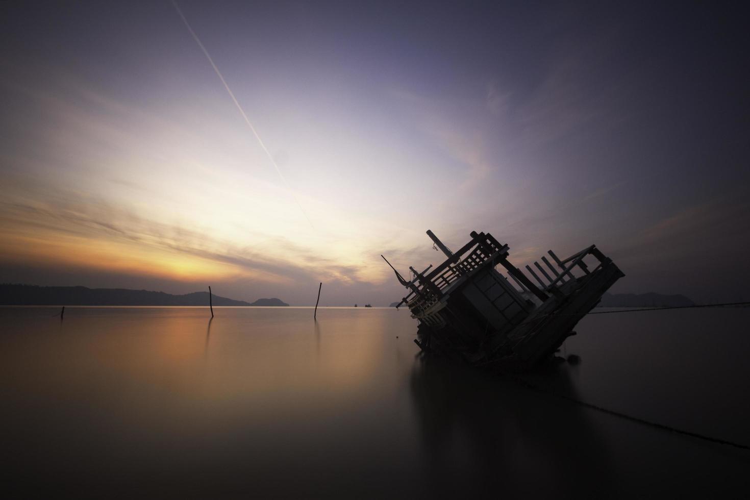 sinkendes Boot im Meer bei Sonnenaufgang foto