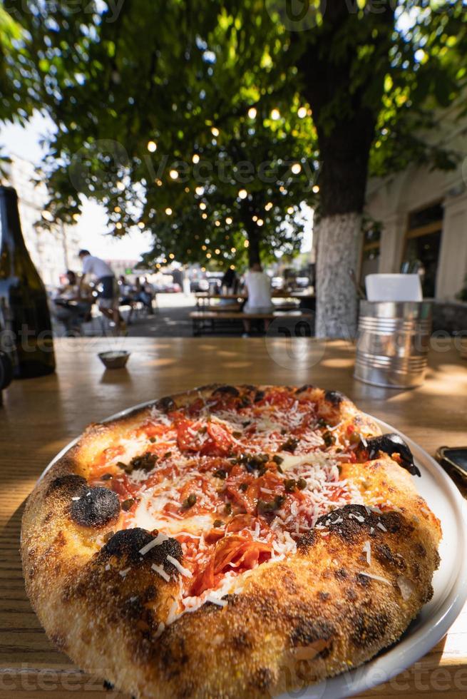 kleine Pizza auf einem Tisch in einem Straßencafé foto