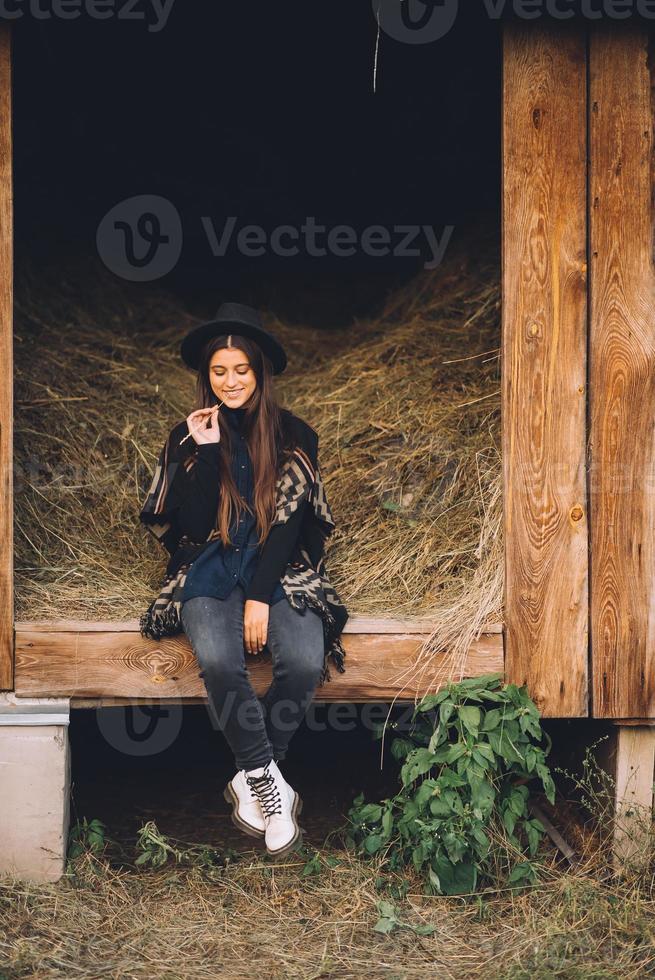 junge brünette frau, die in der scheune sitzt. Landhausstil. foto