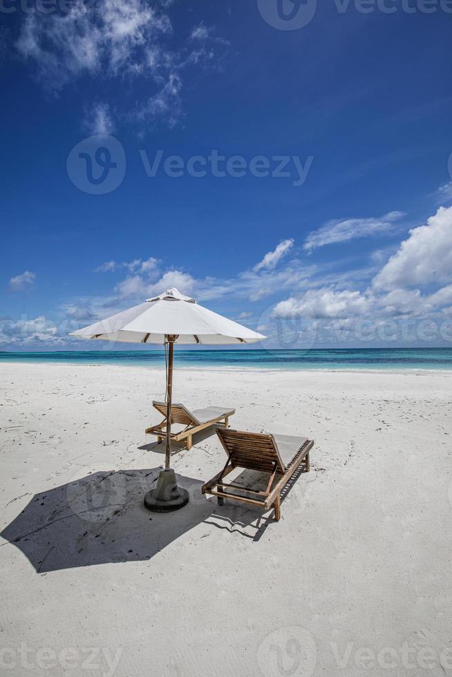 Strandliegen Stühle unter Sonnenschirm und Palme. nahaufnahme weißer sand meer vertikal strand natur. tolle idyllische strandferien sommerferien. luxuspaar romantikreisen, ruhige, sonnige entspannung foto