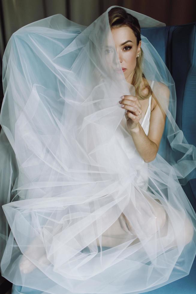 atemberaubende blonde Braut mit tiefen Augen unter blauem Schleier versteckt foto
