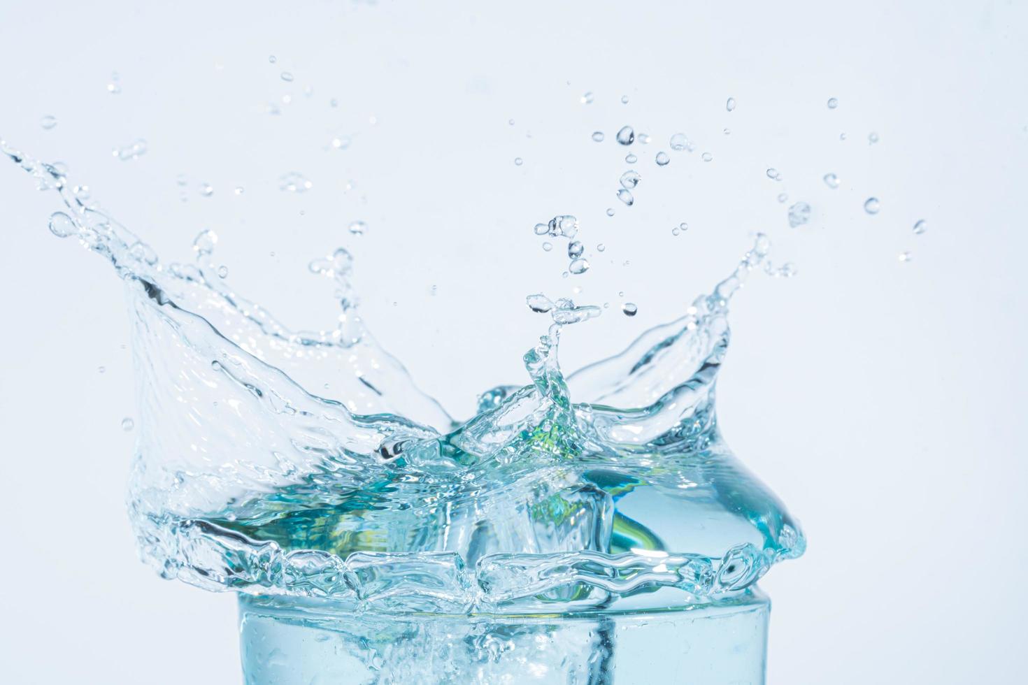 Wasserspritzer in einem Glas auf weißem Hintergrund foto