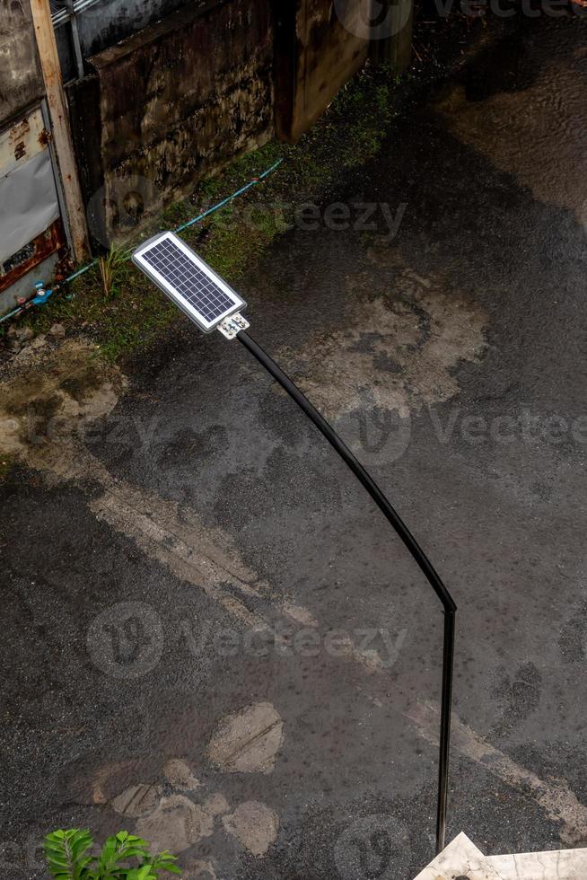 Regen fällt auf ein kleines Solarpanel hinter einer Straßenlaterne in einer kleinen Gasse foto