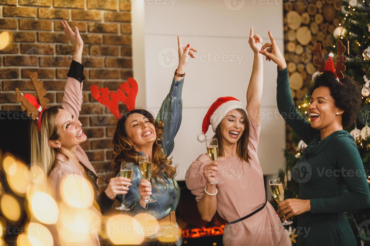 vier multiethnische freundinnen, die spaß haben und zu hause weihnachtsfeier tanzen foto