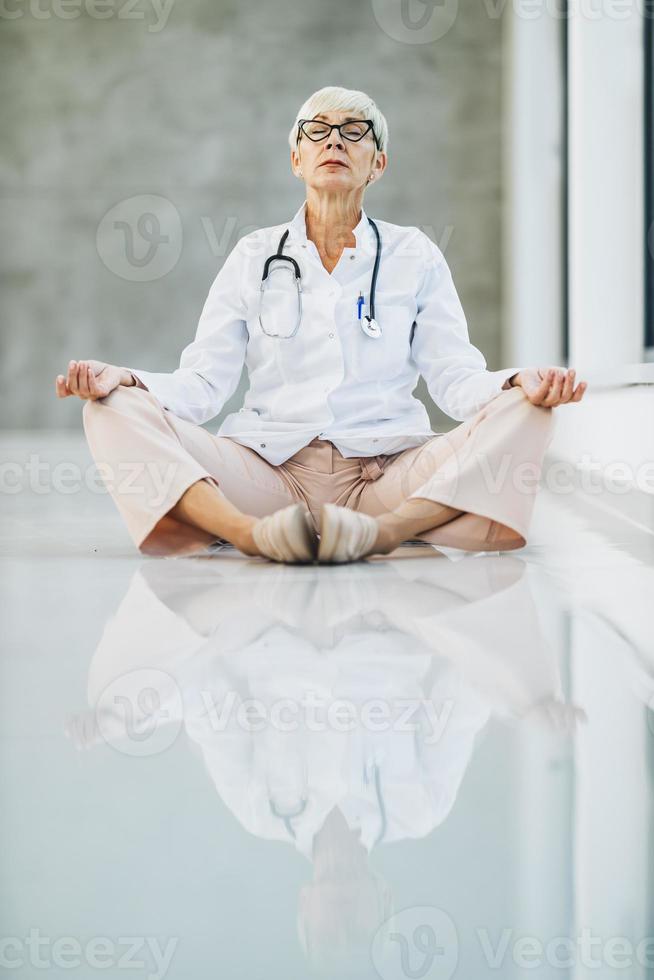 ein Arzt, der im Lotussitz auf dem leeren Krankenhausflur meditiert foto