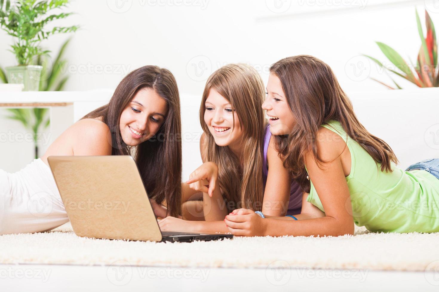 Drei fröhliche Freunde mit Laptop foto