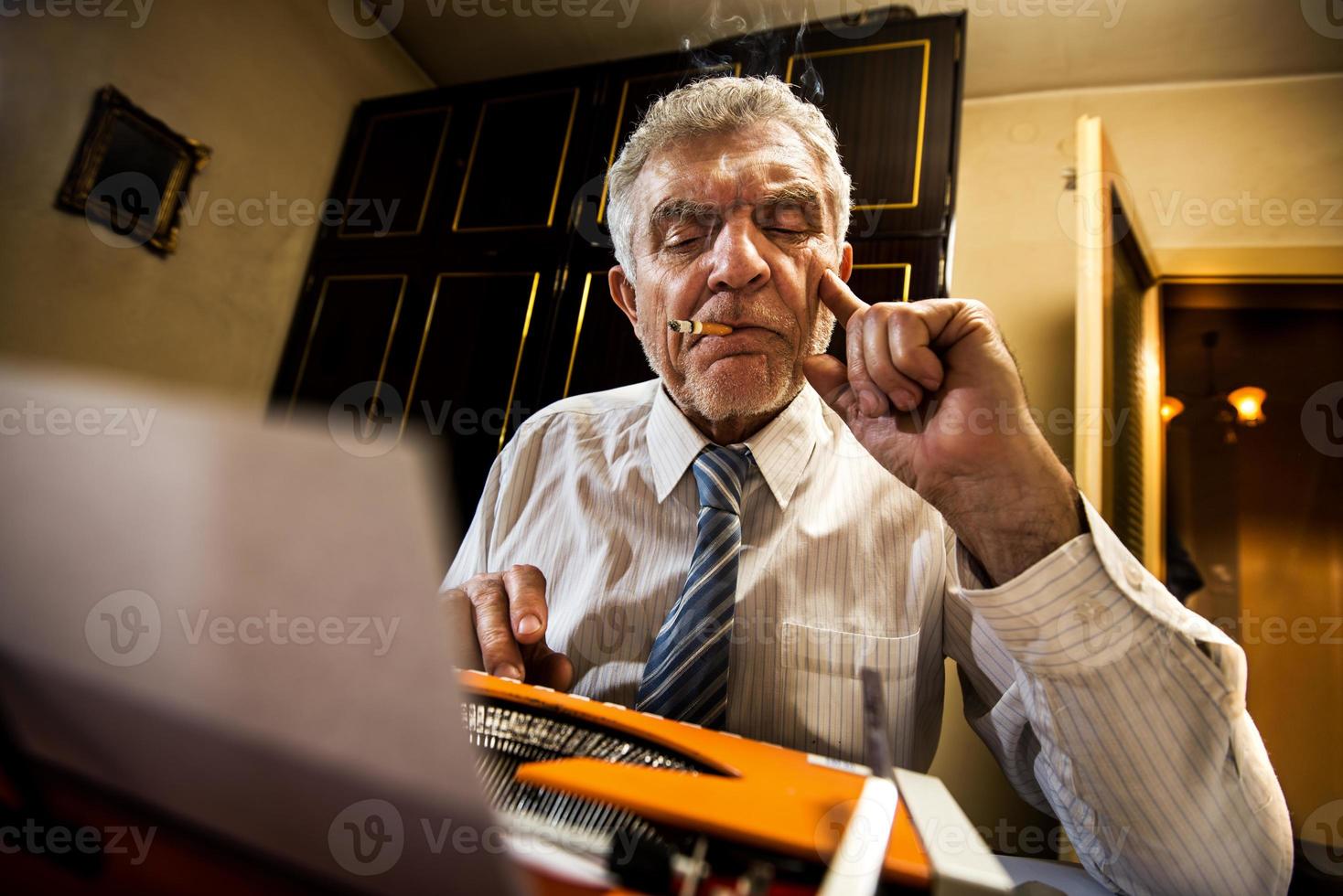 älterer Mann, der auf einer Schreibmaschine schreibt foto