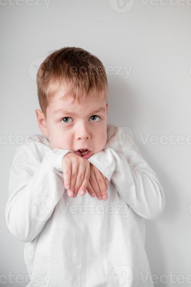 Porträt eines emotionalen Kindes. verängstigter Junge auf weißem Hintergrund. Gesichtsausdruck foto