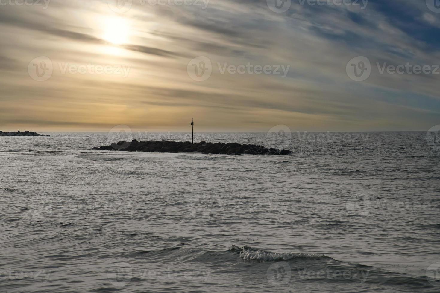Steinbuhnen, Wellenbrecher im Wasser vor der Küste in Dänemark. Am Abend foto