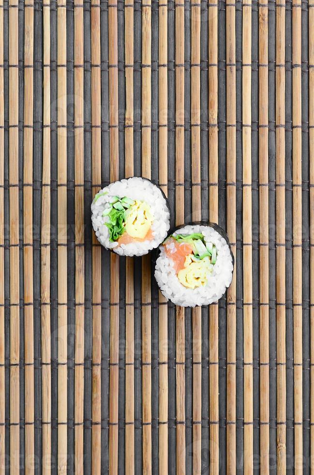 Sushi-Rollen liegen auf einer Nähmatte aus Bambusstroh. traditionelles asiatisches essen. Ansicht von oben. flacher Laienminimalismus mit Kopierraum foto