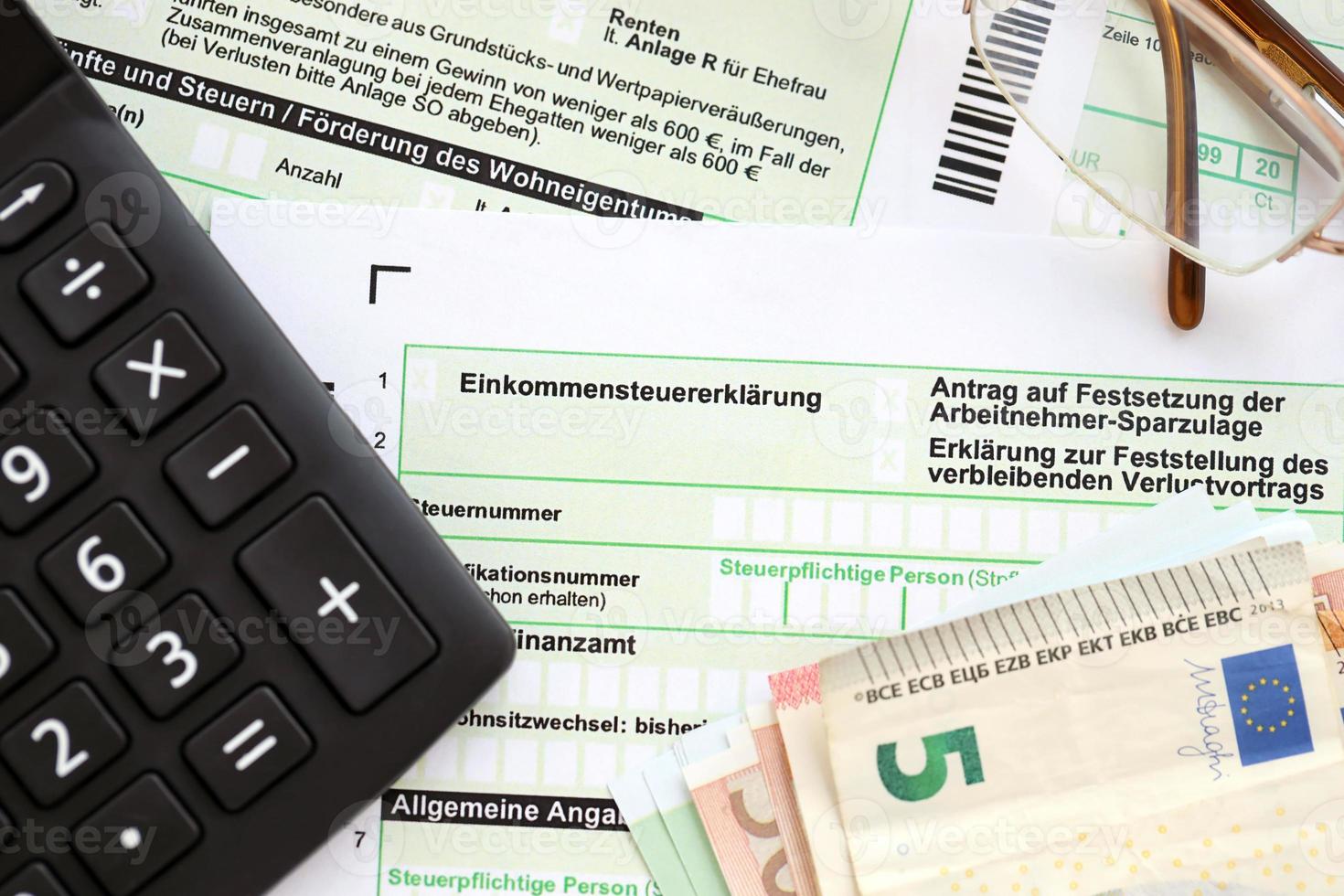 deutsches einkommensteuererklärungsformular mit europäischen euro-geldscheinen und rechner liegt auf dem buchhaltertisch aus nächster nähe. das konzept der steuerzahlzeit in deutschland foto
