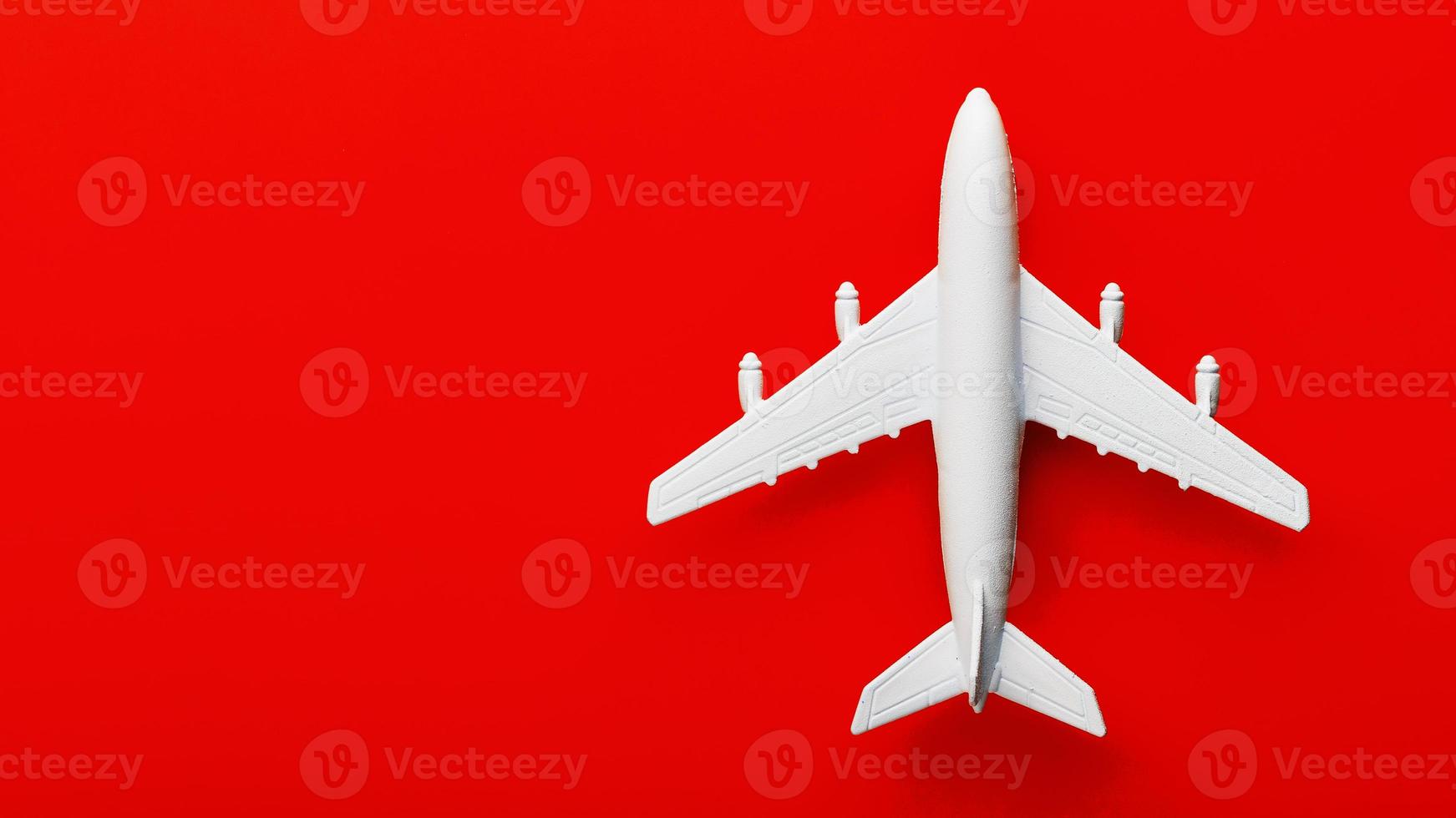 weißes Passagiermodellflugzeug auf einem hellen roten Hintergrund. Freiraum für Text foto
