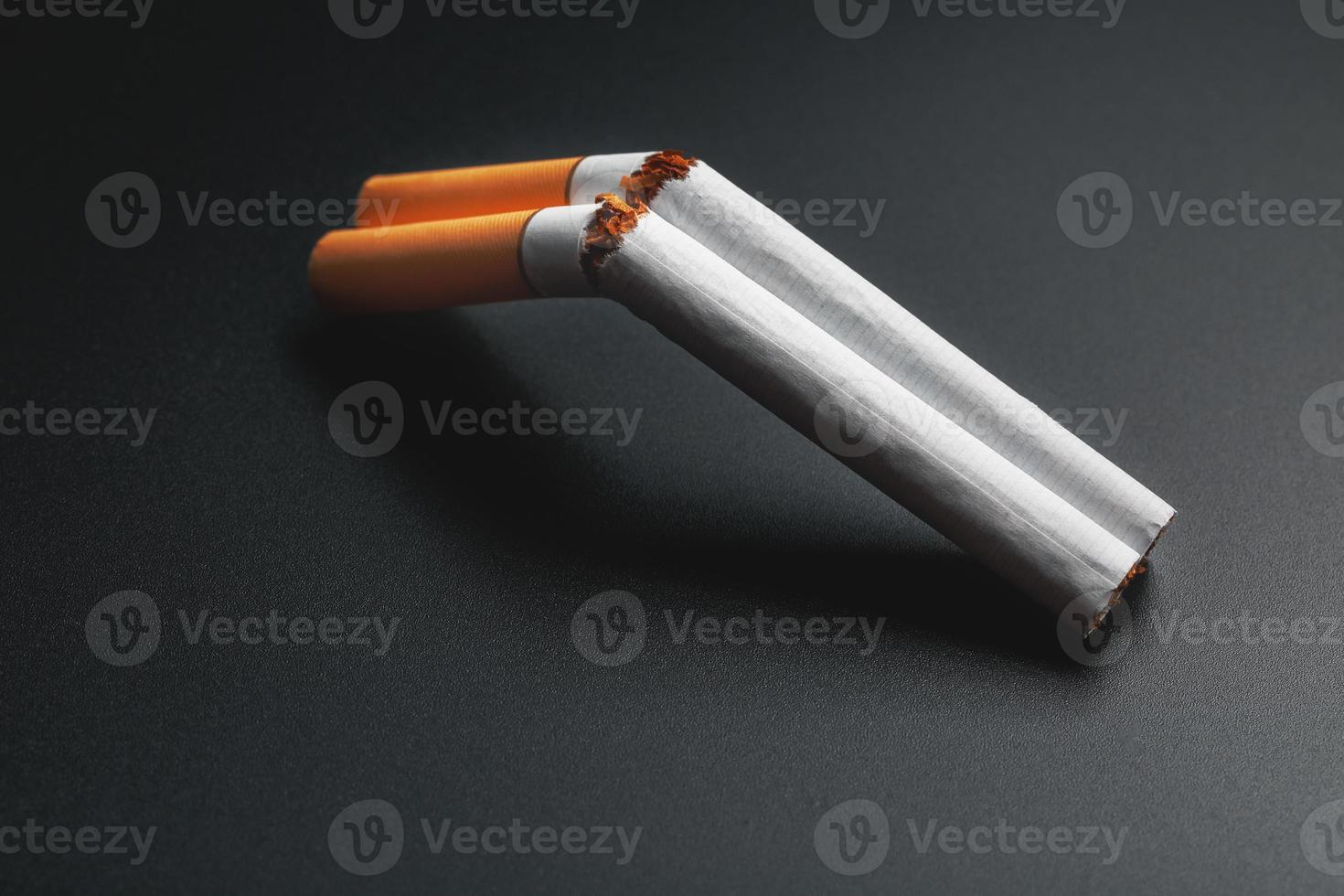 Zwei Zigaretten in Form einer doppelläufigen Schrotflinte auf schwarzem Hintergrund mit Kopierraum. aufhören zu rauchen. das Konzept des Rauchens tötet. foto