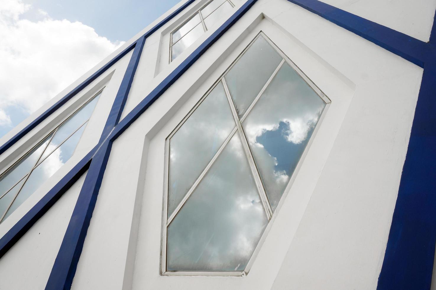 sangatta, ost-kutai, ost-kalimantan, indonesien, 2022 - blau-weiße moderne architektur mit fünfeckigen glasfenstern. blauer himmel und wolkenreflexion. foto