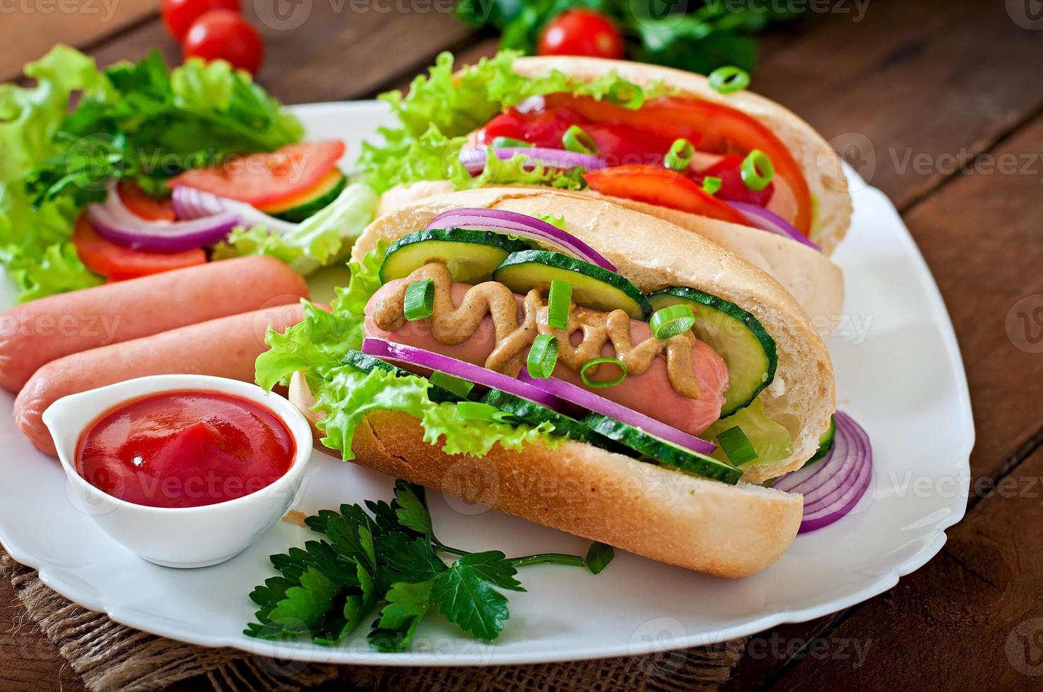 Hotdog mit Ketchup, Senf, Salat und Gemüse auf Holztisch foto