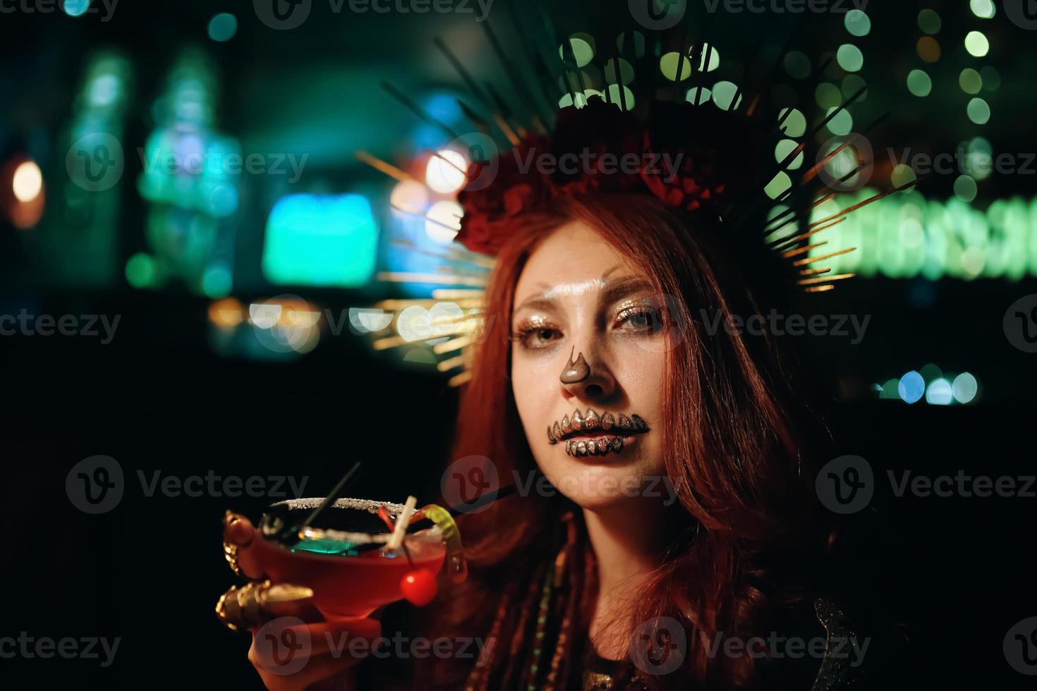 Weibchen mit Skelett-Make-up auf einer Halloween-Party hält Cocktail. foto