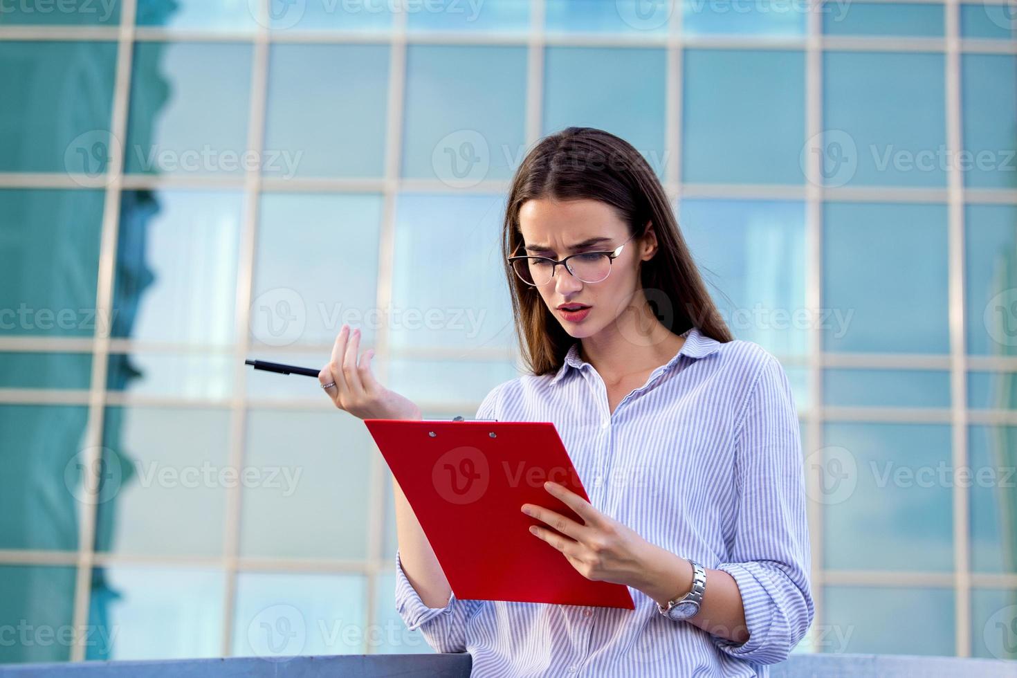 Executive Business Woman mit Zwischenablage vor dem städtischen Hintergrund foto