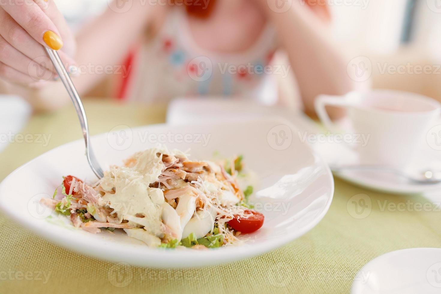 Frauenhand hält Gabel in einem Salatteller. foto