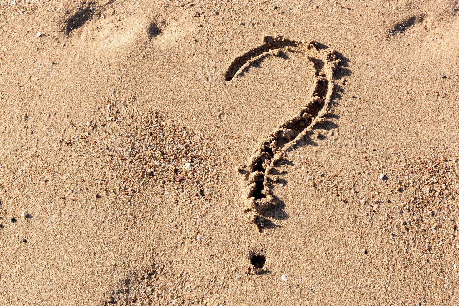 Fragezeichenzeichen am Sandstrand nahe dem Meer. konzept von dilemma, antwort und frage foto