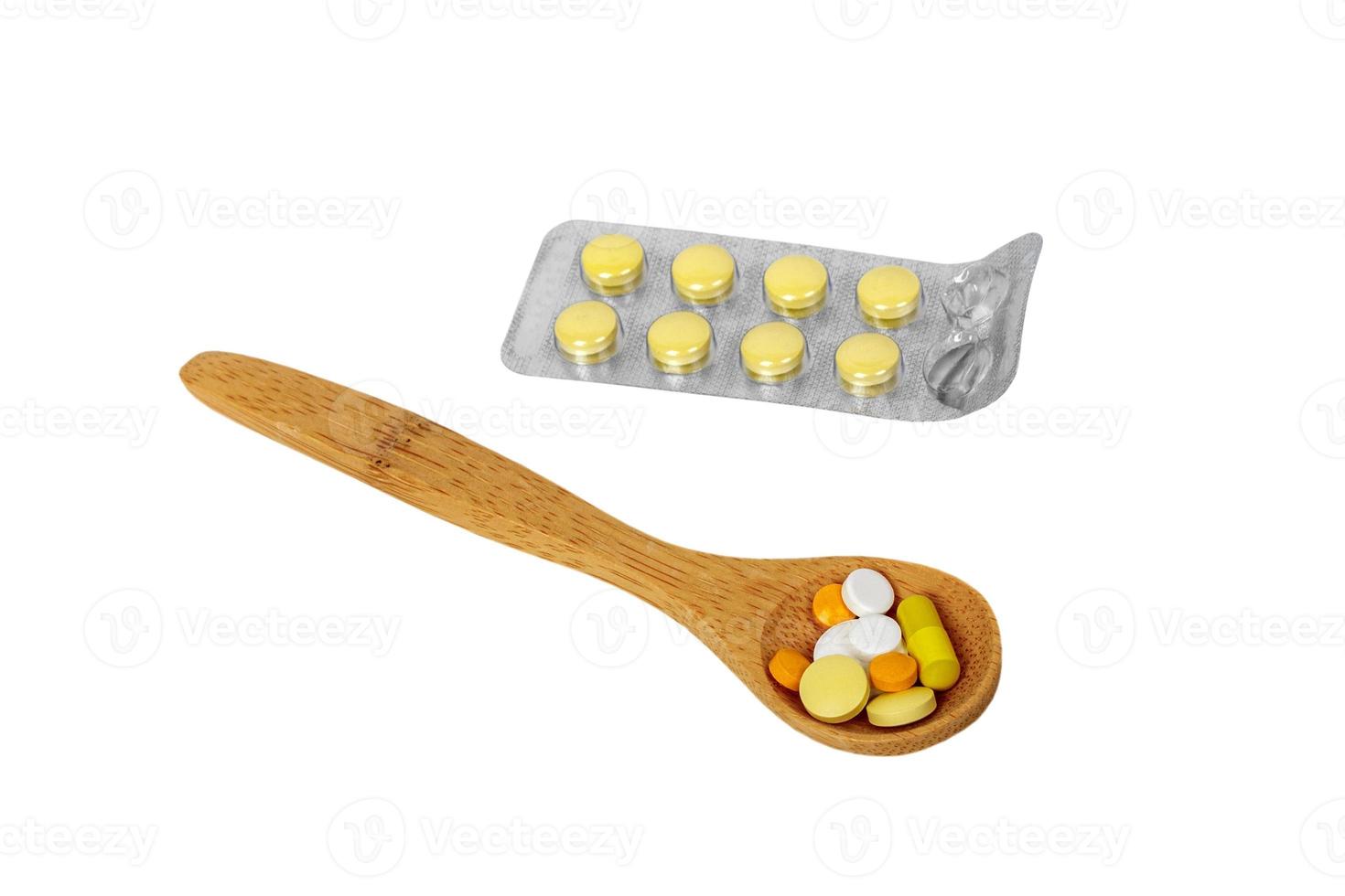 Holzlöffel mit Pillen und Tabletten in Blisterpackungen auf dem Tisch. isoliert foto