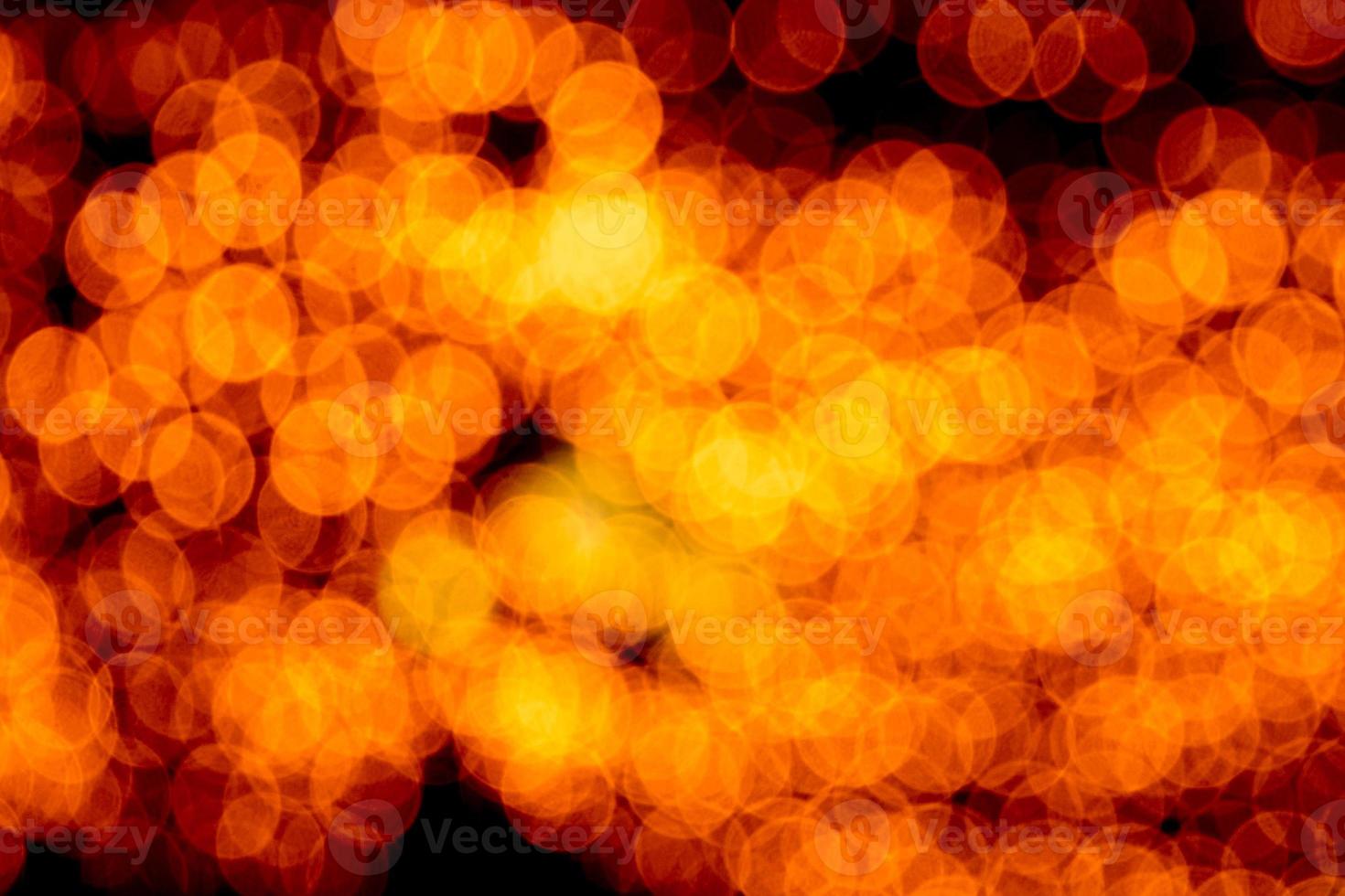 Unfokussiertes abstraktes orangefarbenes Bokeh auf schwarzem Hintergrund. defokussiert und verschwommen viele runde licht foto