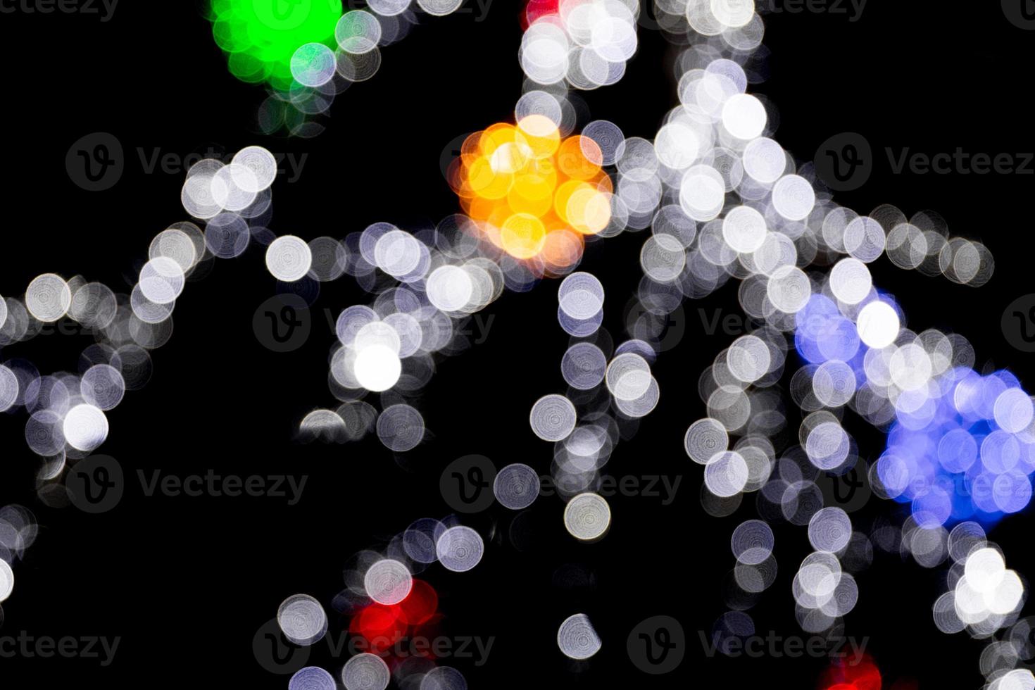 Unfokussiertes abstraktes buntes Bokeh mit roter, grüner, oranger und blauer Lampe auf schwarzem Hintergrund. defokussiert und verschwommen viele runde licht foto