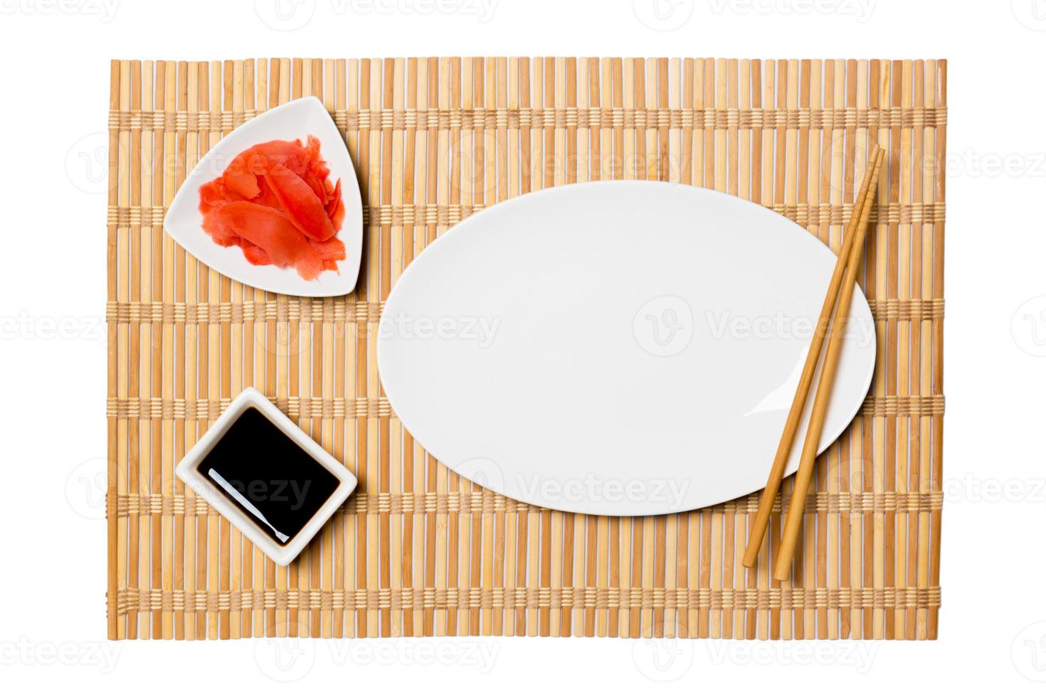 leere ovale weiße Platte mit Essstäbchen für Sushi, Ingwer und Sojasauce auf gelbem Bambusmattenhintergrund. Draufsicht mit Kopierbereich für Ihr Design foto