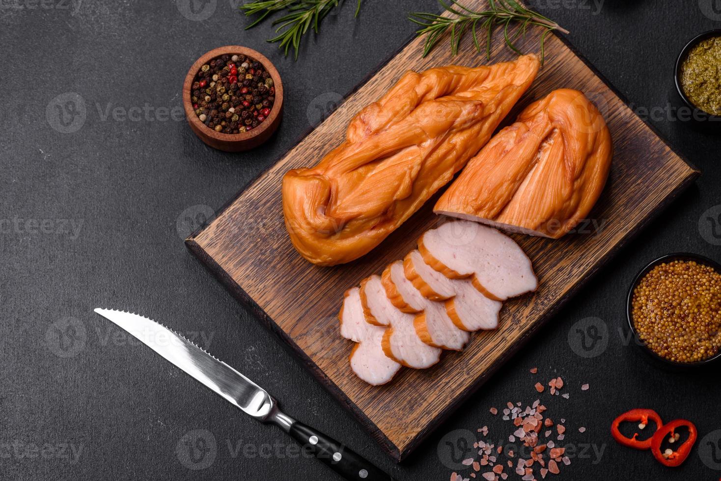 lecker geräuchertes Hähnchenbrustfilet mit Gewürzen und Kräutern auf einem Holzschneidebrett foto