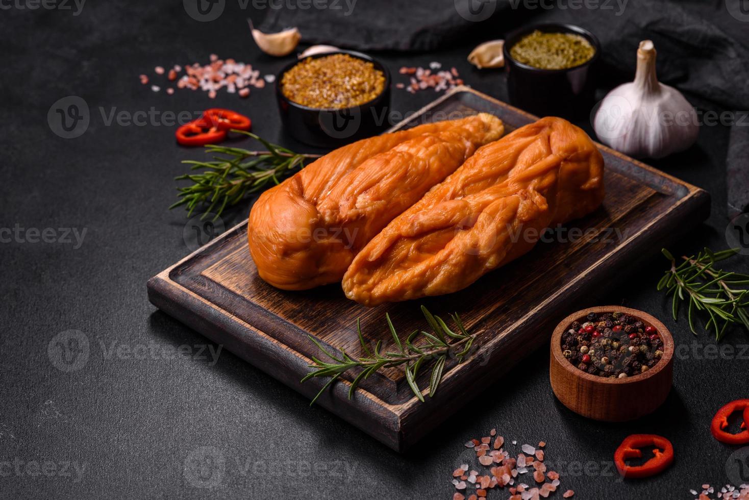 lecker geräuchertes Hähnchenbrustfilet mit Gewürzen und Kräutern auf einem Holzschneidebrett foto