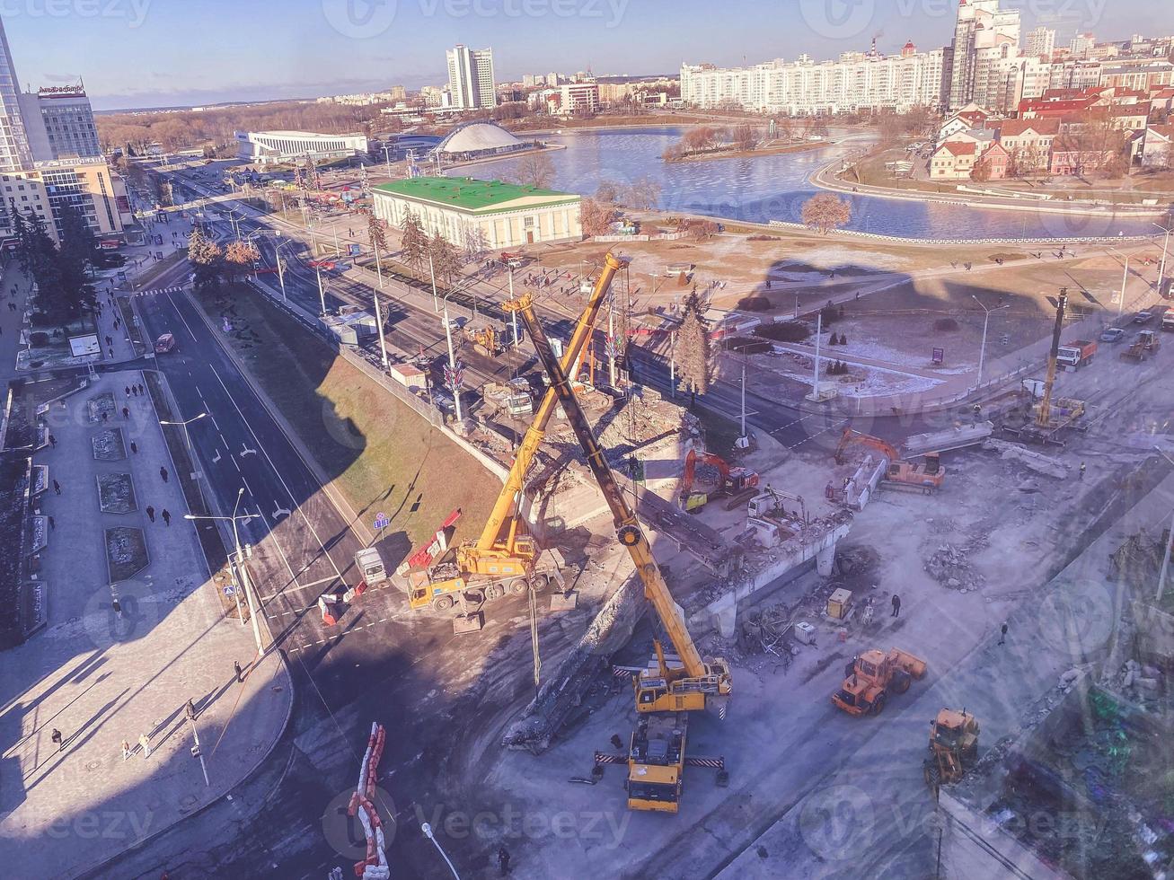 Bau einer neuen Überführung in der Innenstadt. In der Nähe des Flusses, des Wanderwegs und vieler Gebäude. hohe Kräne auf der Straße foto