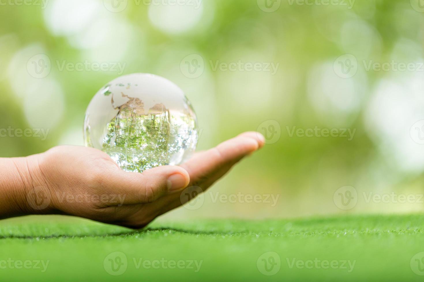 Kristallkugel, die als erzählendes Objekt verwendet wird. Naturpark mit Bäumen im Hintergrund. Hand für Umwelt, Soziales und Governance in nachhaltigem und ethischem Wirtschaften auf grünem Hintergrund. foto