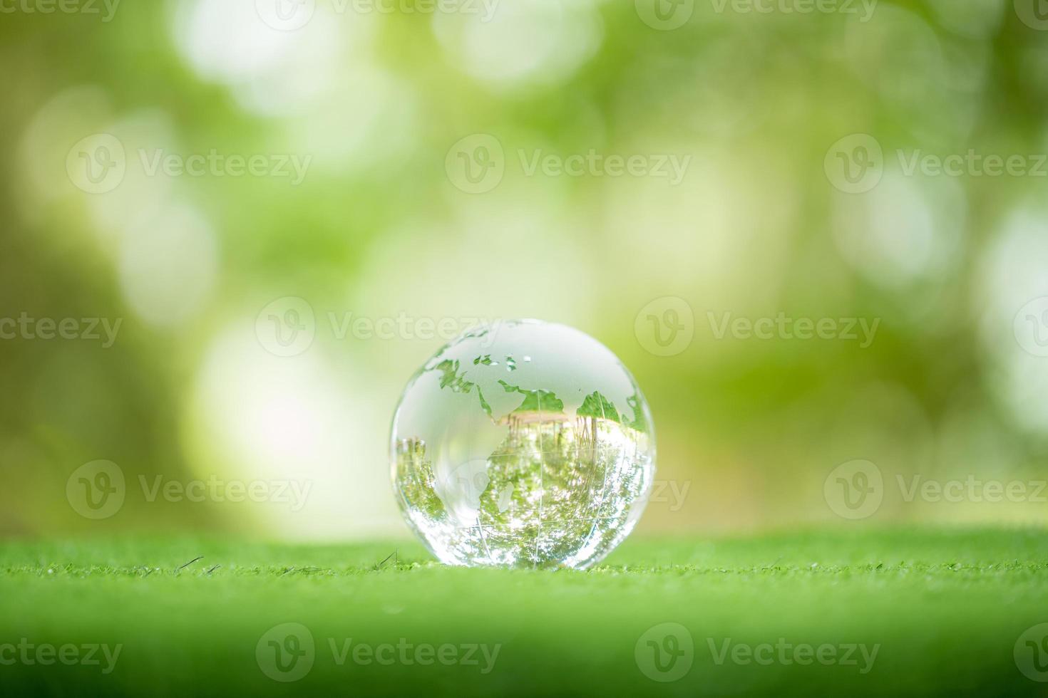 Nahaufnahme der Kristallkugel, die auf Gras in einem Wald ruht - Umweltkonzept. Umwelt, Soziales und Governance in nachhaltigem und ethischem Geschäft auf grünem Hintergrund. foto