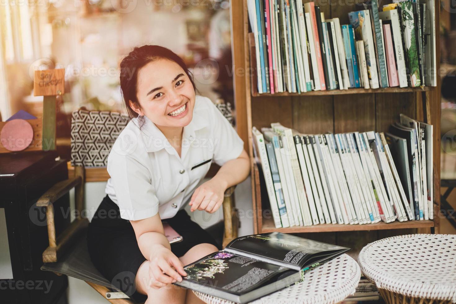 Universitätsuniform Mädchen Teenager liest ein Buch suchen Kamera glücklich Lächeln Vintage Farbton foto