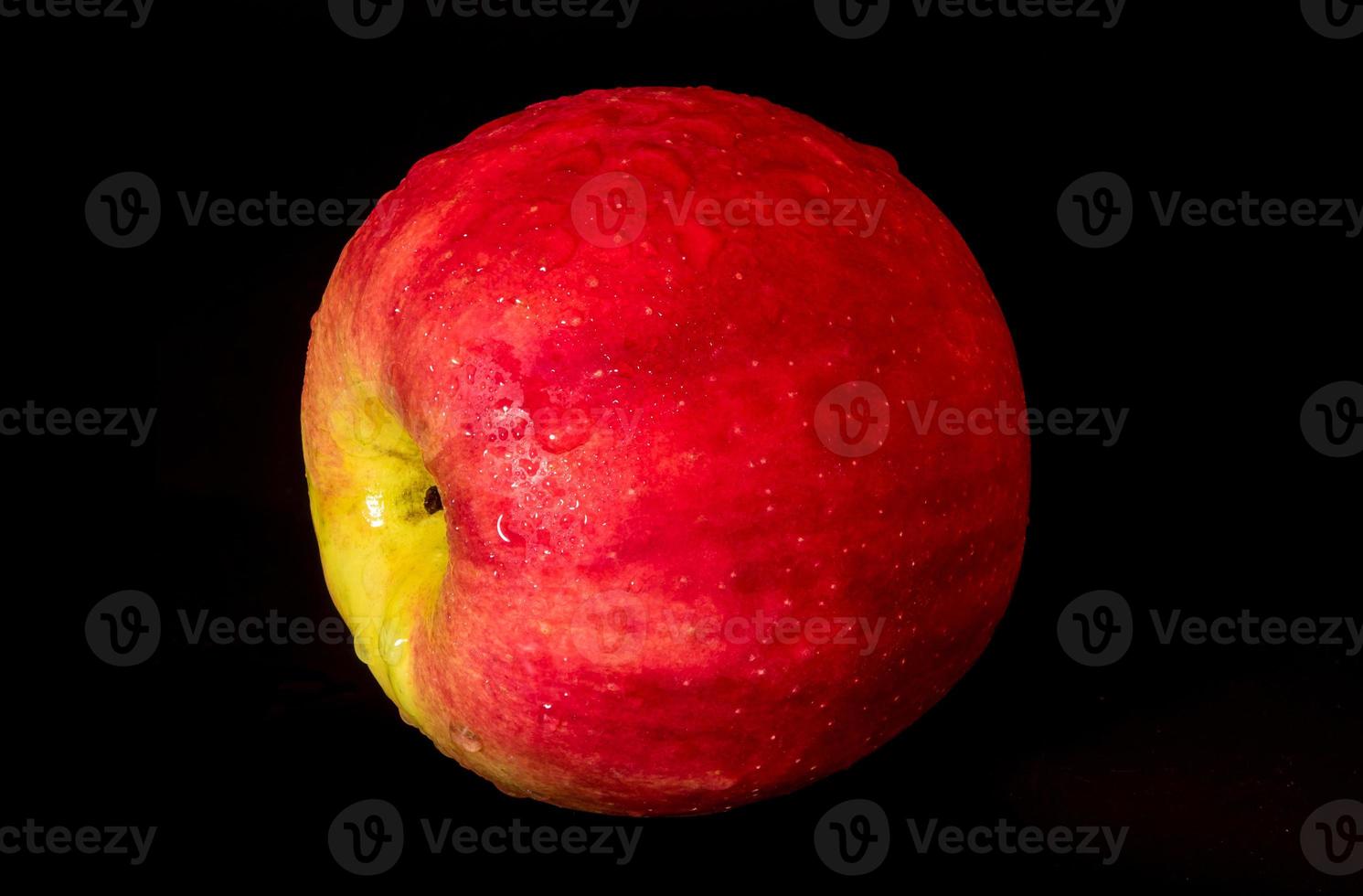 Wassertropfen auf glänzender Oberfläche von rotem Apfel auf schwarzem Hintergrund foto