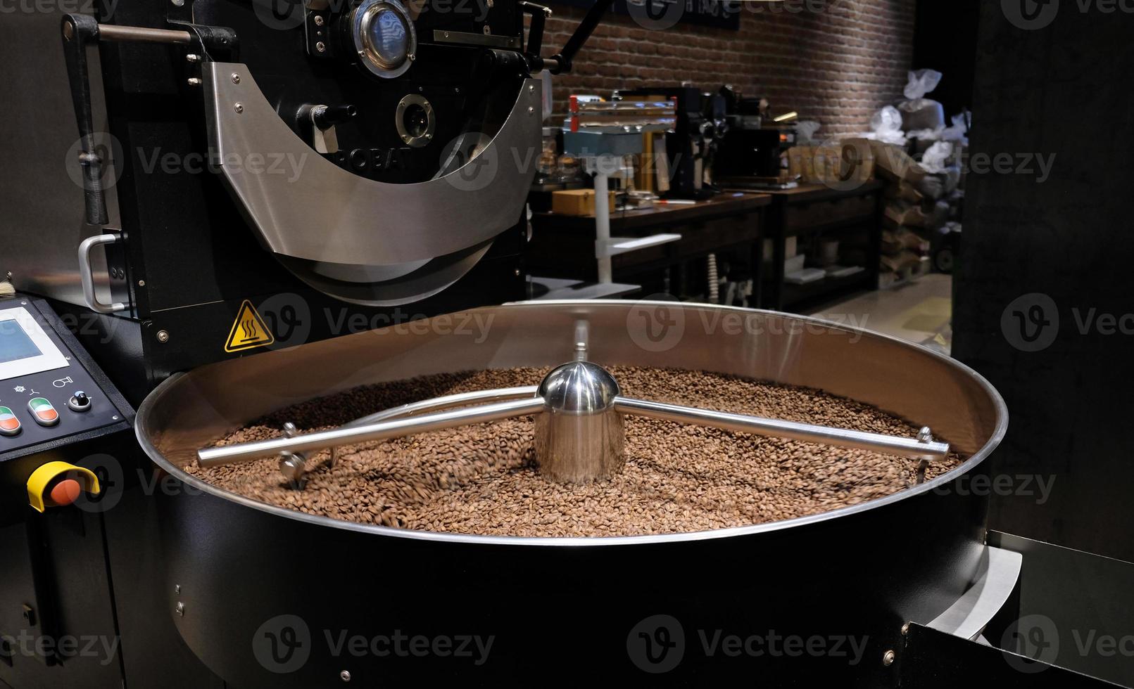 Kaffeeröstmaschine beim Kaffeerösten. Kaffeebohnen mischen. geröstete rotierende Kühler professionelle Maschinen und frische braune Kaffeebohnen Bewegung Nahaufnahme dunkles Foto im Werk.