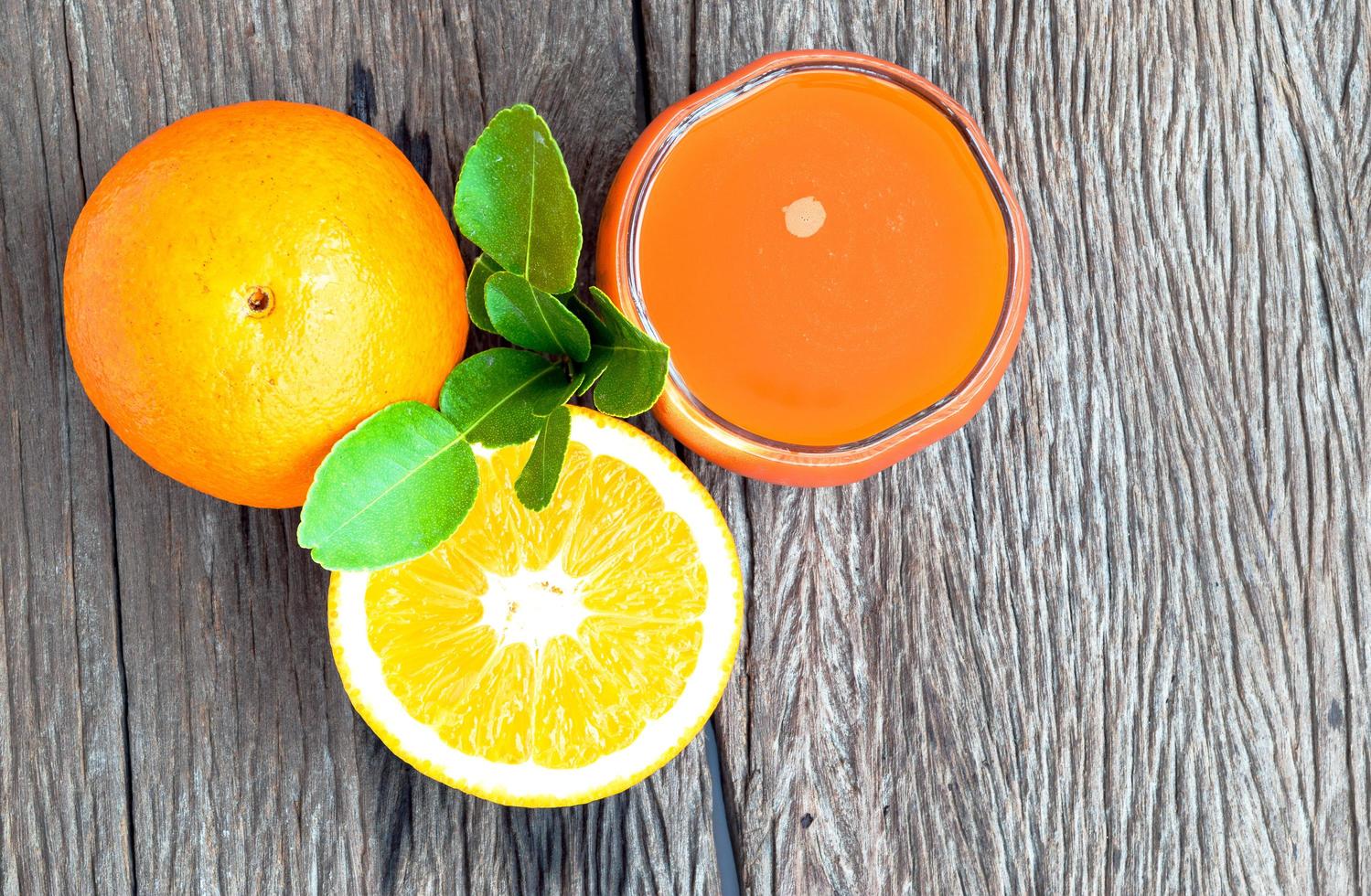 Orangensaft und Orangen auf einem Holzboden foto