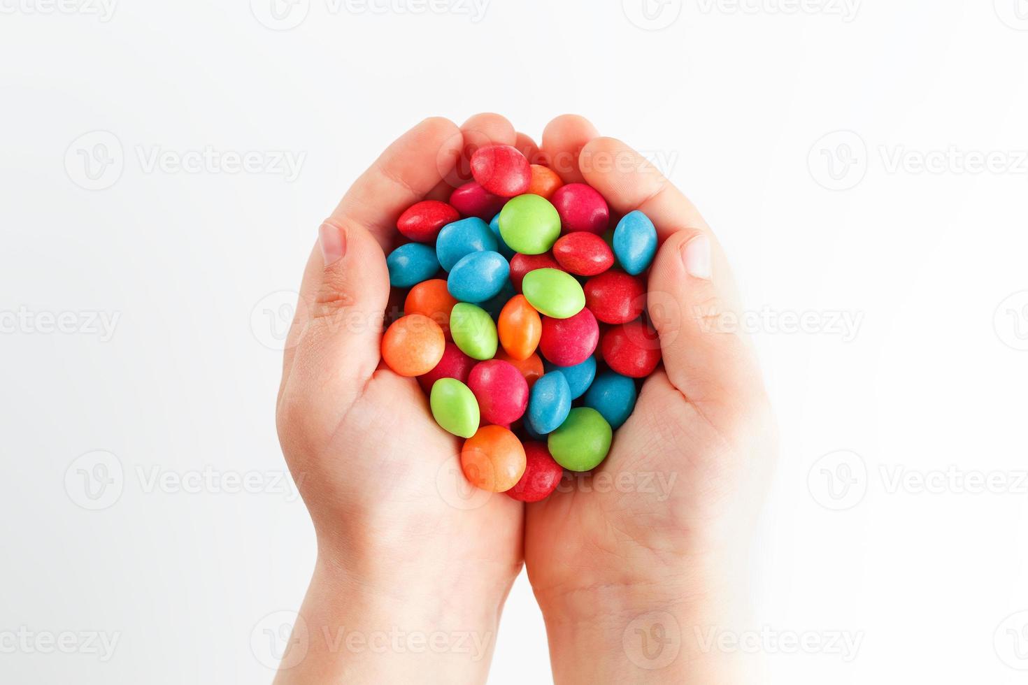 Mehrfarbige Bonbons in den Händen eines Kindes auf einem weißen, isolierten Hintergrund foto