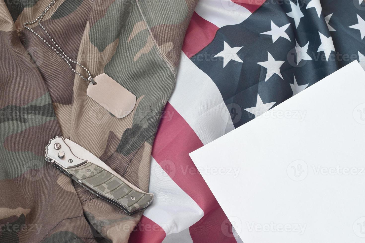 Army Dog Tag Token und Messer liegen auf alter Tarnuniform und gefalteter Flagge der Vereinigten Staaten foto