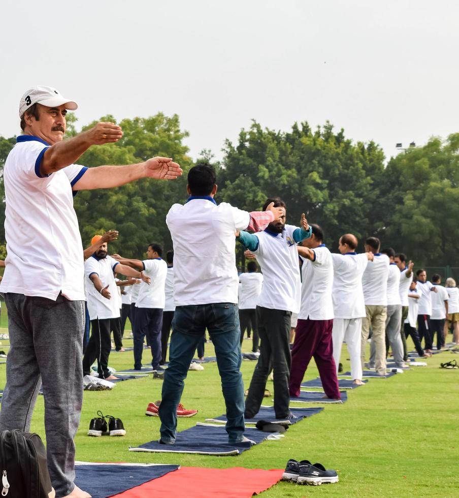 neu-delhi, indien, 21. juni 2022 - gruppen-yoga-übungssitzung für menschen im yamuna-sportkomplex in delhi am internationalen yoga-tag, große gruppe von erwachsenen, die an yoga-kursen im cricket-stadion teilnehmen foto