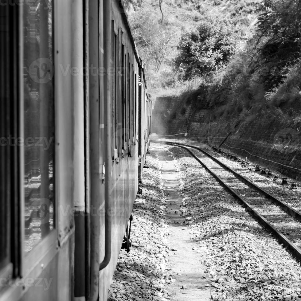 spielzeugeisenbahn, die sich am berghang bewegt, schöne aussicht, eine seite des berges, eine seite des tals, die auf der eisenbahn zum hügel fährt, inmitten grüner naturwälder. spielzeugeisenbahn von kalka nach shimla in indien-schwarz und weiß foto