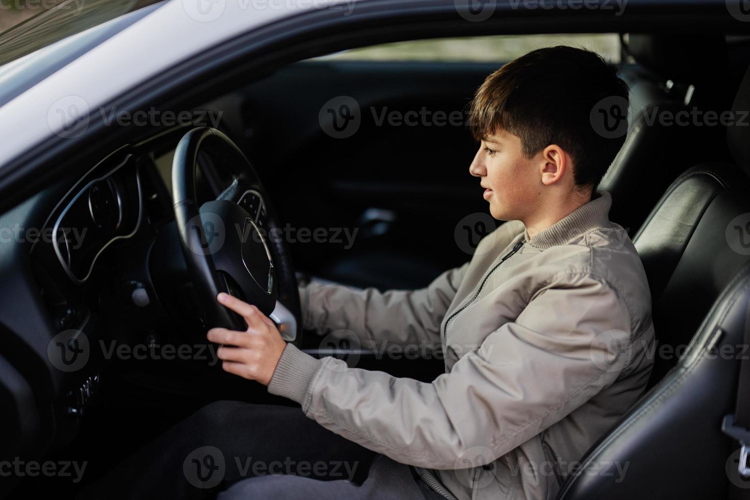 Teenager-Junge sitzt im Muscle-Car. junger Teenager-Fahrer. foto