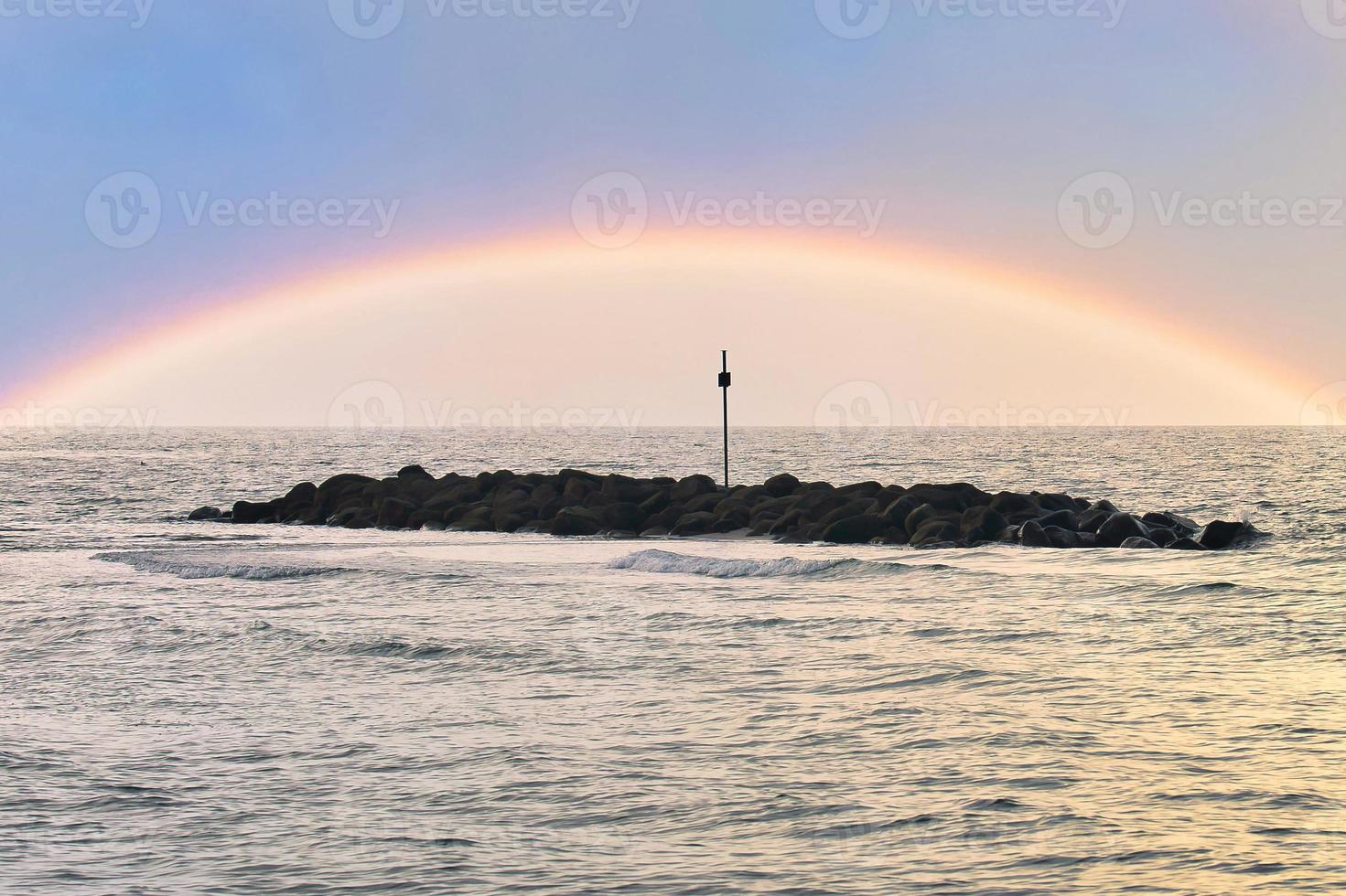 Steinbuhnen, Wellenbrecher im Wasser vor der Küste in Dänemark. Regenbogen foto