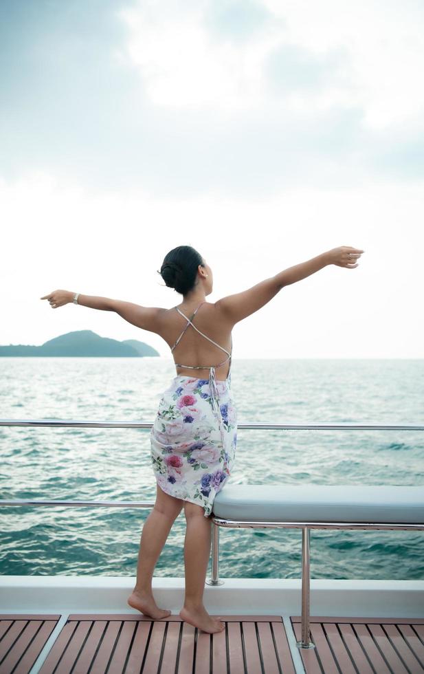 ein asiatisches mädchen auf einem yachtstand, um die frische luft vom meer zu erhalten foto